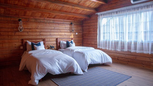 Comfortable log cabin bedroom featuring twin beds, natural wood design and soft lighting.